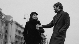 Ein Schwarzweiss-Foto eines Paares, das Hände hält, während es entlang eines Bürgersteigs geht