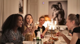 Ein Foto von schönen ausländischen Frauen, die Wein haben und Geselligkeit haben, während sie an einem ausgefallenen Esstisch sitzen