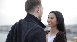 Ein Foto eines ausländischen Mannes und einer asiatischen Frau, die sich glücklich in die Augen schauen