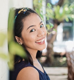  Ein Foto einer lächelnden asiatischen Frau, die an eine Wand lehnt