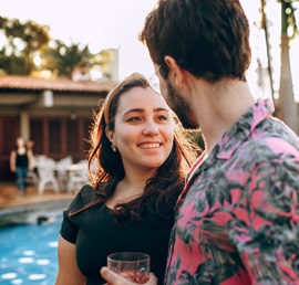 Ein Foto eines Mannes und einer Latina-Frau, die einen Drink teilen, während sie glücklich ein Gespräch genießen
