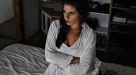  Ein Foto einer Frau, die mit verschränkten Armen im Bett sitzt